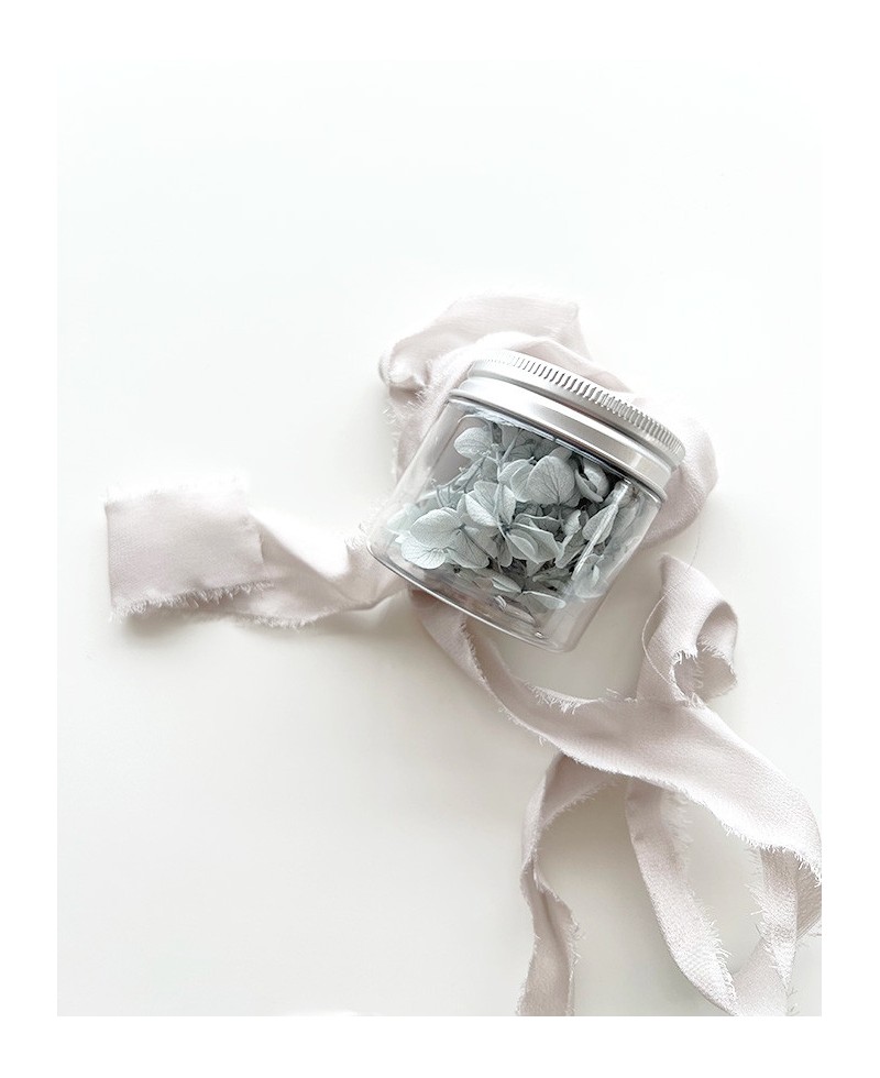 Glas mit getrockneten Blumen in pudriger blauer Farbe Glas mit getrockneten Blumen in pudriger blauer Farbe